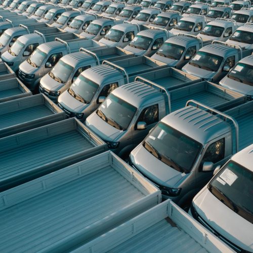 Aerial shot of multiple silver pickup trucks aligned in rows, showcasing symmetry and industrial production.
