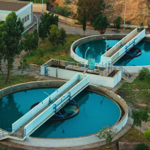 Drone shot of an advanced water purification plant surrounded by trees.